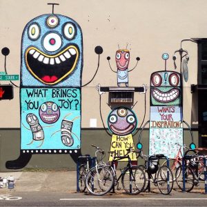 A street mural with whimsical robotic characters in front of a bike rack.